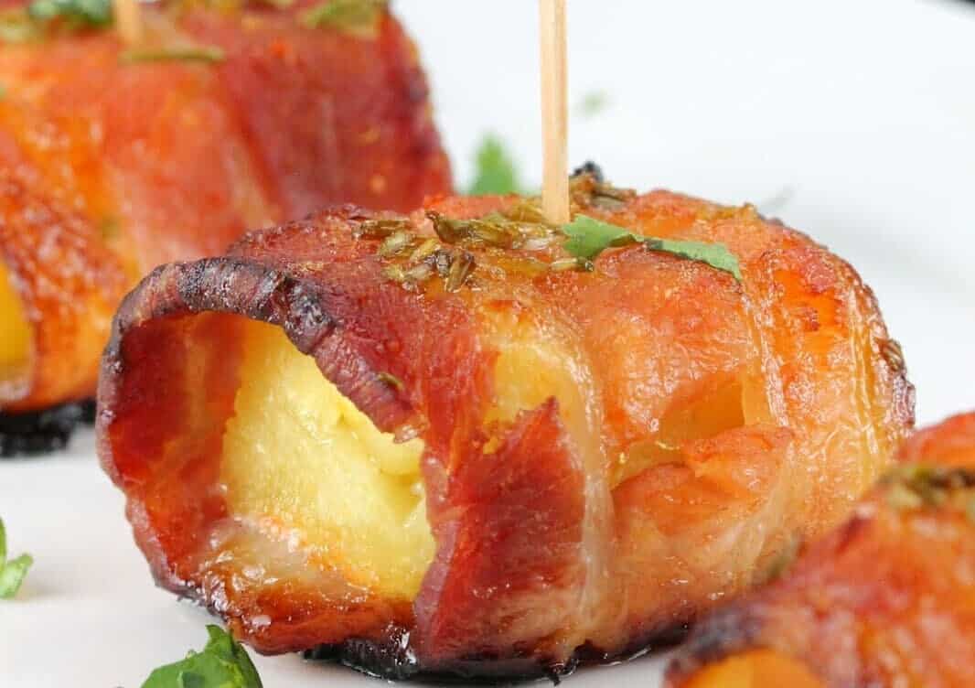 Bacon is wrapped around pineapple and glazed with a sweet and smokey sriracha-honey sauce in this spectacular appetizer.