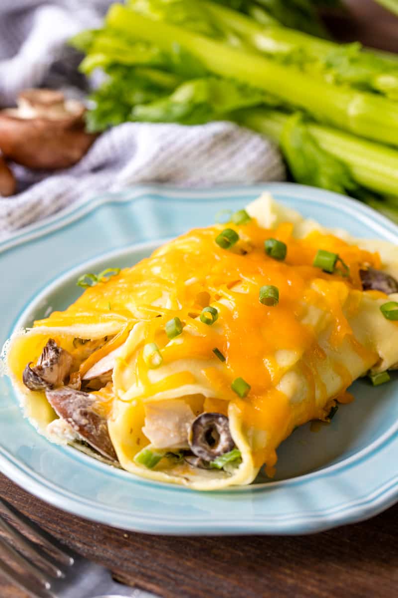 Chicken Crepes covered in melted cheese on a blue plate.