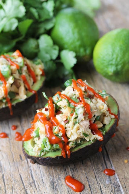 Avocado halves stuffed with Thai-inspired tuna, garnished with chopped cilantro and drizzled with spicy Asian chili sauce