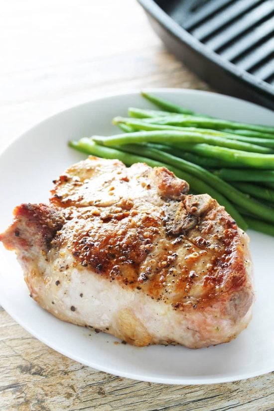 Thick cut juicy bone-in pork chop with a side of green beans