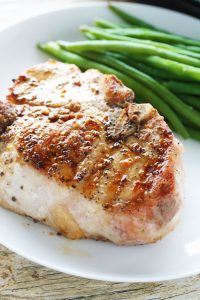 Thick cut juicy bone-in pork chop with a side of green beans