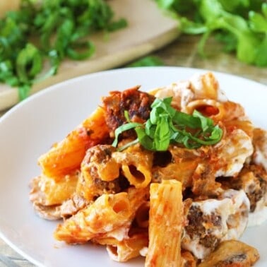 Baked ziti with meatballs and mushrooms on a white plate.