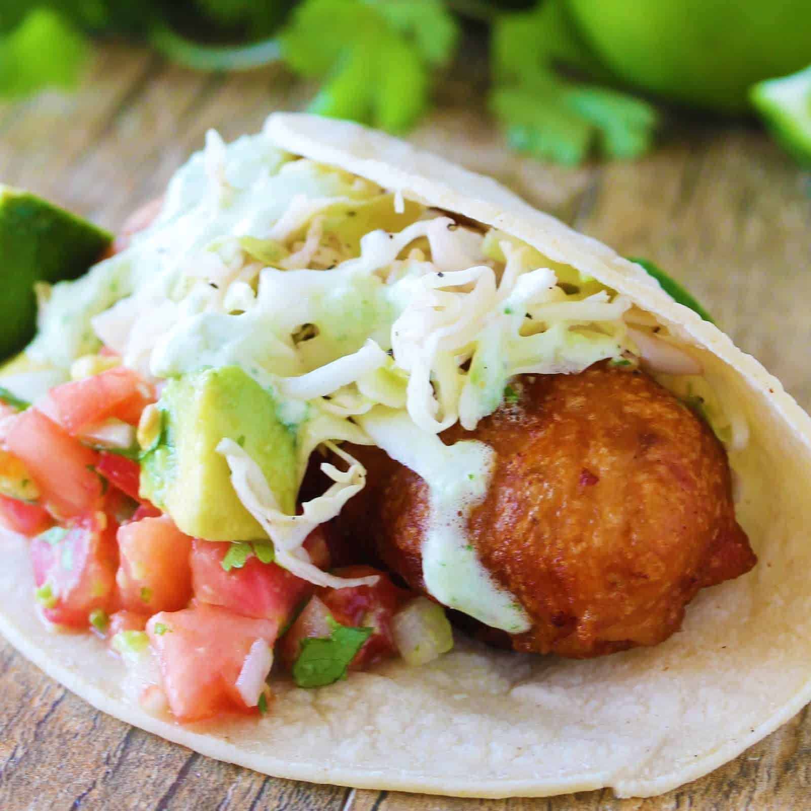 Crispy battered cod is topped with avocado salsa, simple slaw and jalapeno, wrapped in a corn tortilla and served with a lime wedge