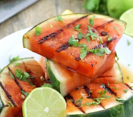 Grilled Watermelon on a white plate with half a lime.