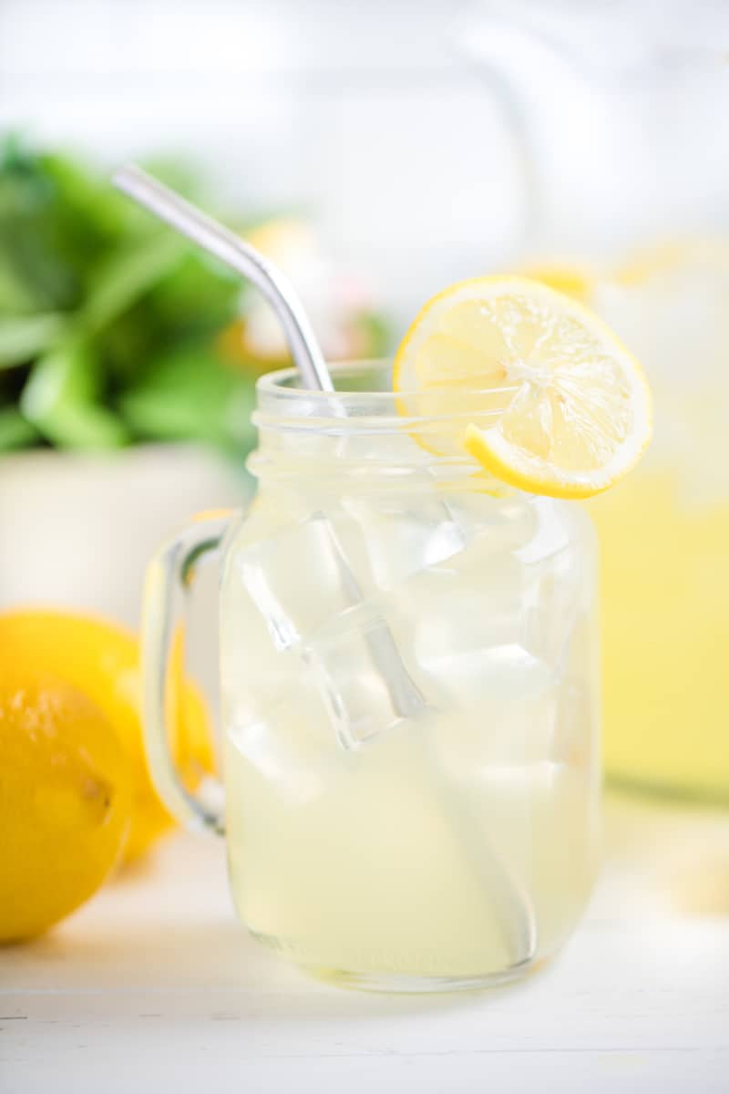 Homemade Lemonade in a glass mug with a metal straw and a sliced lemon.