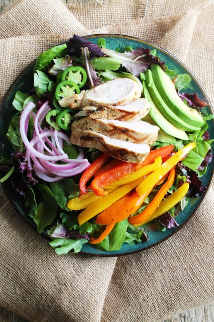 Grilled Mojo Chicken Salad served up with slices of avocado and jalapeno, grilled bell peppers, and pickled red onion over a bed of lettuce.