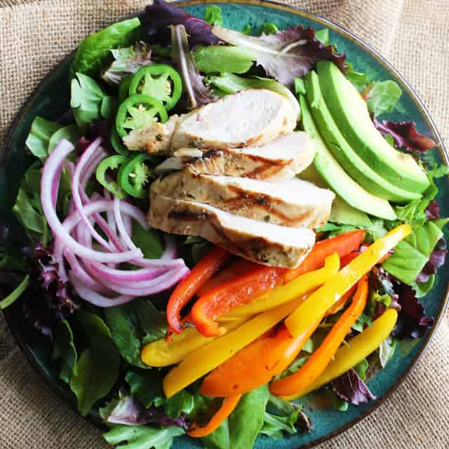This Mojo Grilled Chicken Salad is a healthy dinner that is full of flavor. Chicken is marinated in a Cuban mojo (citrus-garlic sauce) and grilled to perfection. Served up in a delicious salad with sliced avocado, grilled bell peppers, pickled red onion, and jalapeno.