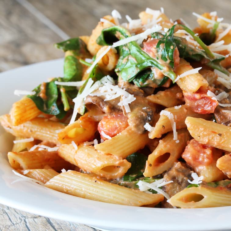 Penne Rosa tossed with a creamy red sauce with a kick and tomatoes, mushrooms, and spinach. Freshly grated parmesan is sprinkled on top.