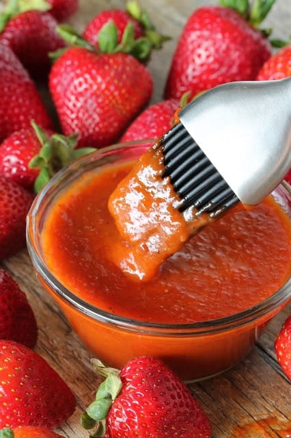 A basting brush dips into a bowl of Strawberry Chipotle BBQ Sauce