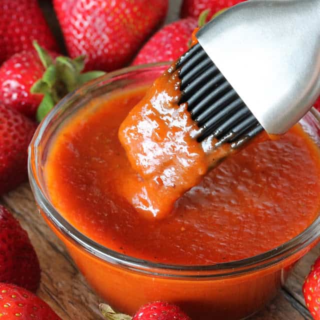 A basting brush dips into a bowl of Strawberry Chipotle BBQ Sauce