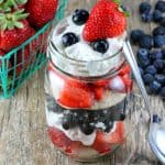 Red, White, and Blueberry Mason Jar Shortcake on a wooden counter.