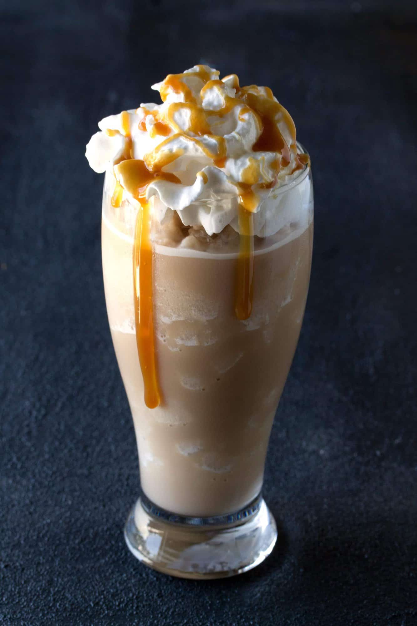 Salted Caramel Frappe in a tall glass with caramel running down the side.