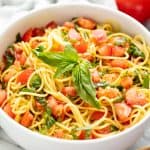 Tomato Pasta in a white bowl topped with basil.