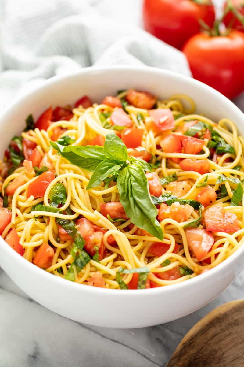 Tomato Pasta in a white bowl topped with basil.