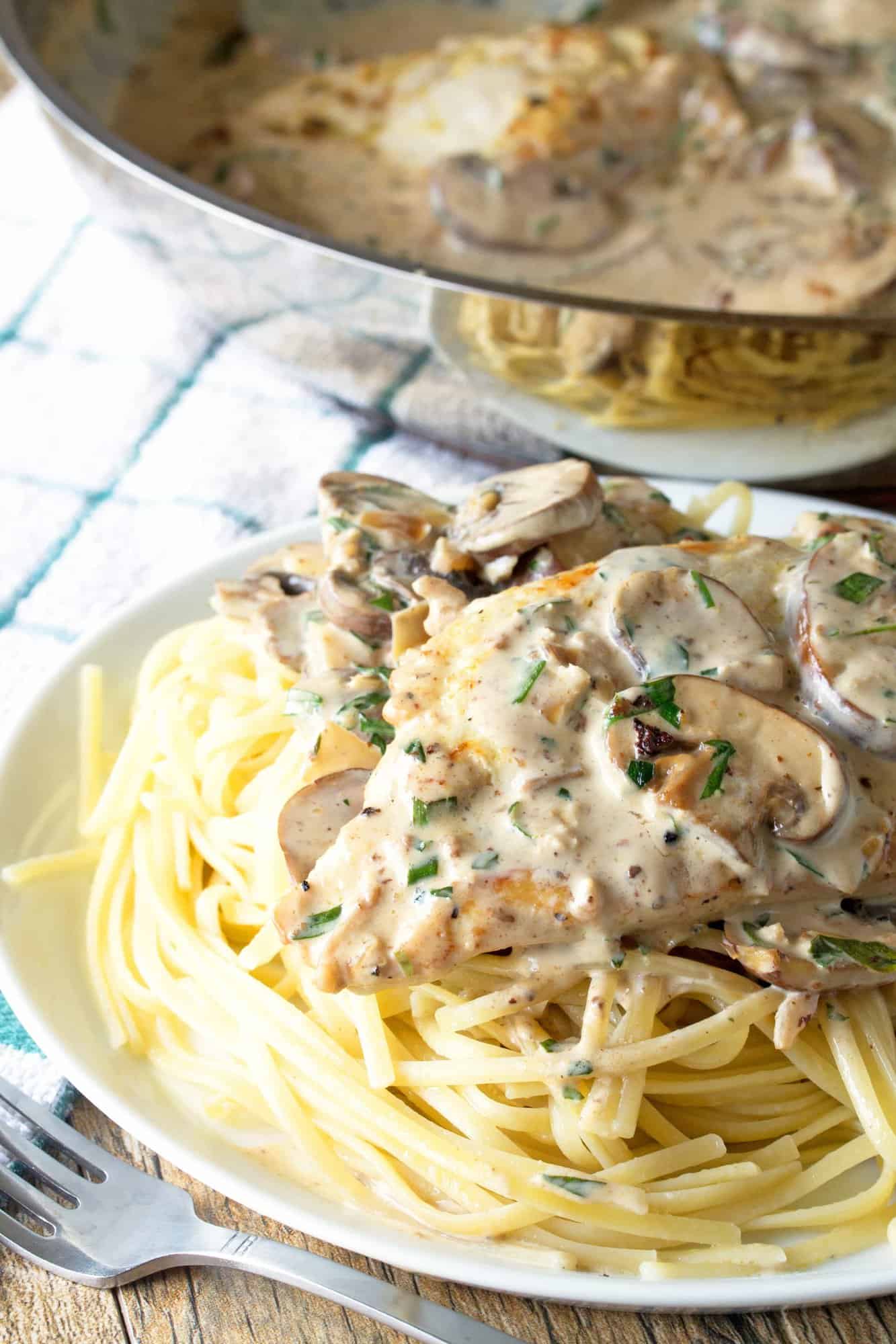 Tarragon Dijon Chicken over some pasta on a white plate.