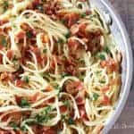 Eggless Spaghetti Carbonara with rich flavor from bacon and garlic and its creamy texture from parmesan cheese and cream. Sprinkled with freshly chopped parsley in a skillet.