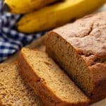 Banana Bread with two slices taken off the end, laying on each other all on a cutting board.