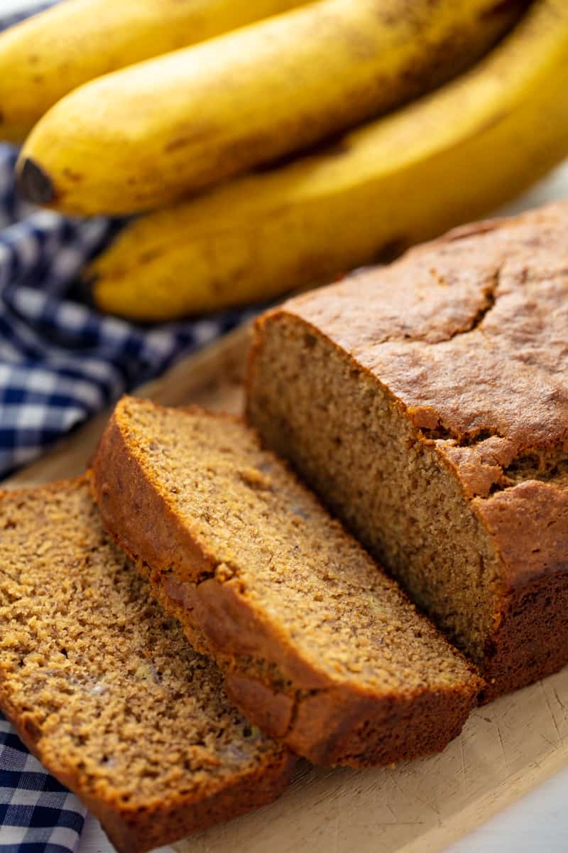 Banana Bread with two slices taken off the end, laying on each other all on a cutting board. 