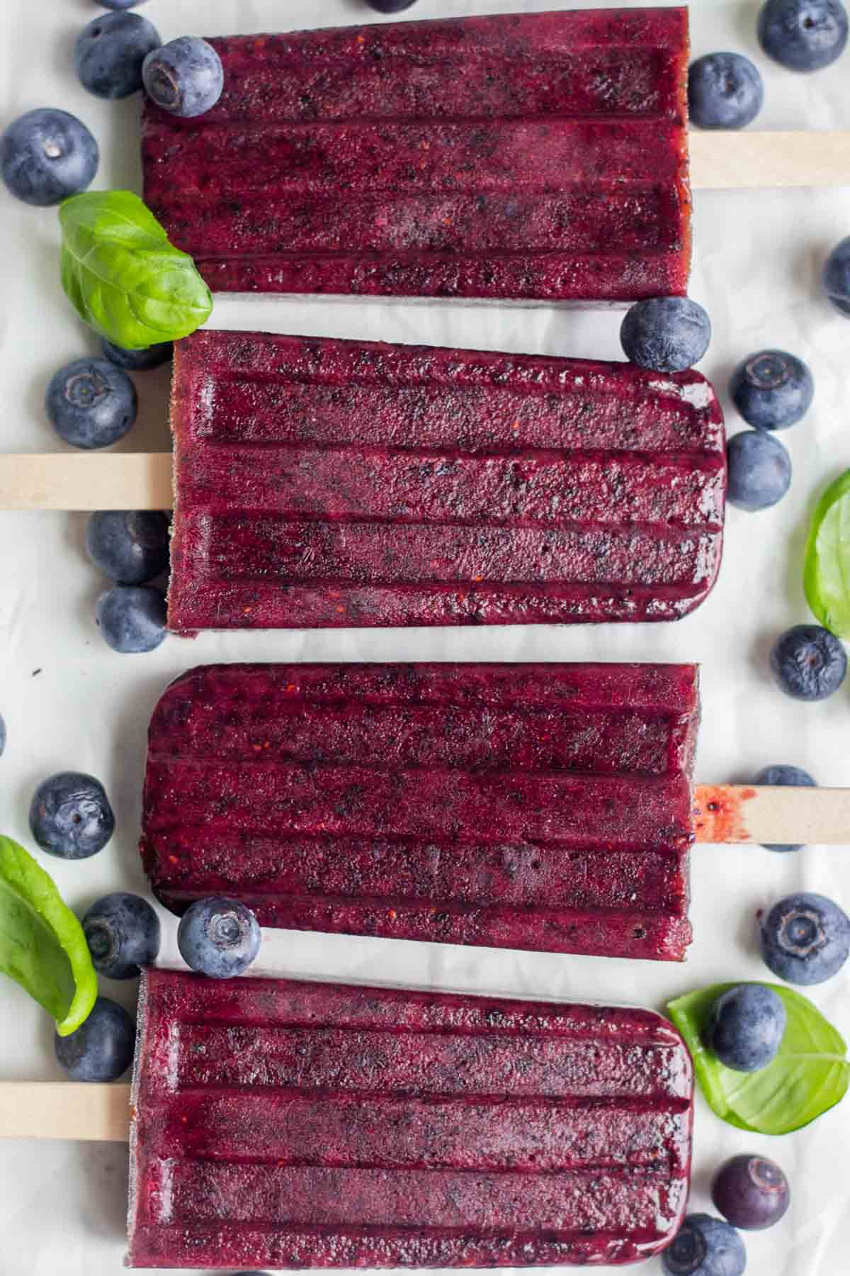 Bird's eye view of four Blueberry Basil Popsicles sitting on a countertop.