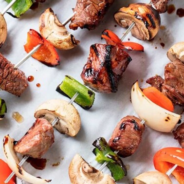 Five Marinated Steak Kebabs on parchment paper.