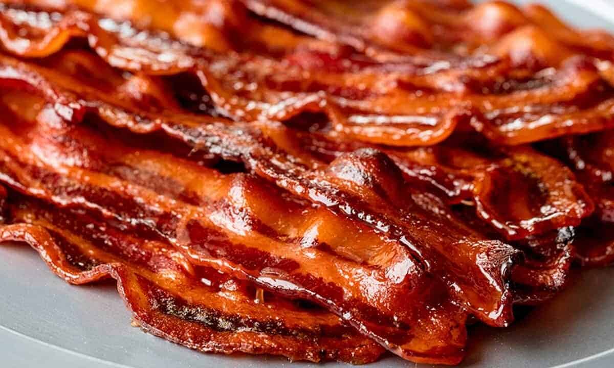 Close-up view of Spicy Maple Candied Bacon stacked and slayed on a grey serving dish.
