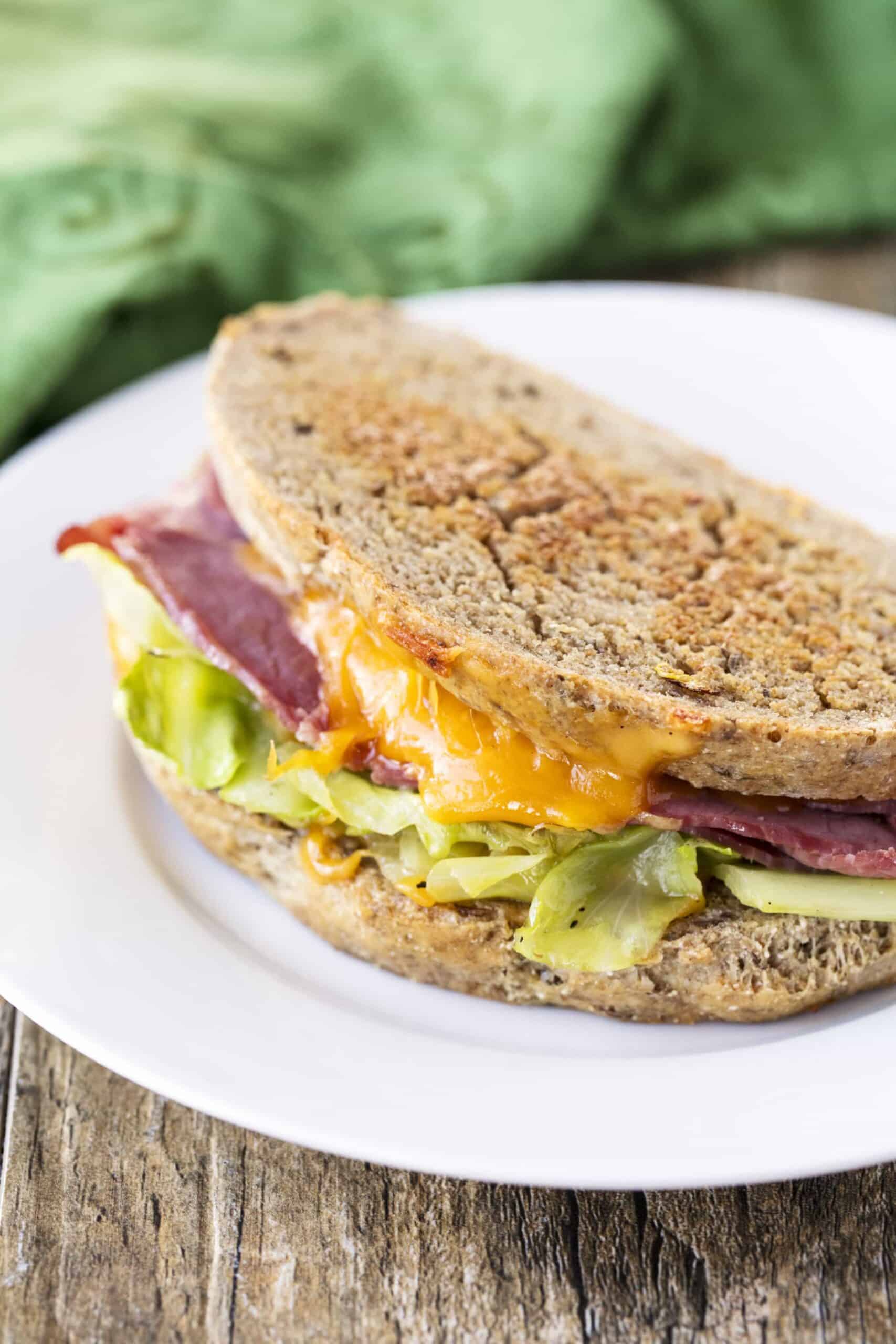 Corned Beef and Cabbage Grilled Cheese on Rye on a white plate.