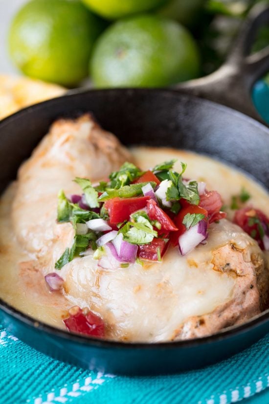 Fiesta lime chicken topped with cilantro, onions and peppers in a cast iron skillet