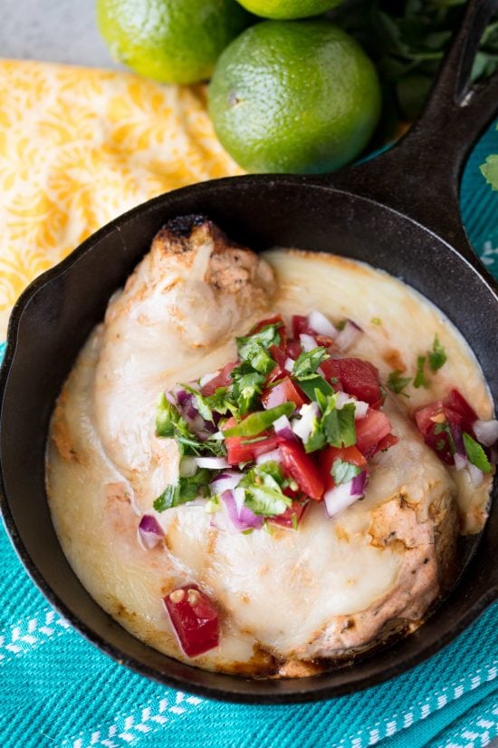 Bird's eye view of fiesta lime chicken topped with cilantro, onions and peppers in a cast iron skillet.