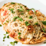 A close up view of a chicken breast that has been stuffed with the flavors of a ricotta lasagna filling and smothered with cheese.