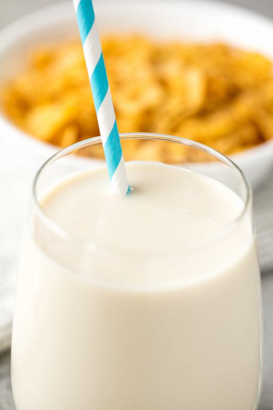 A glass of cereal milk with a blue and white striped straw