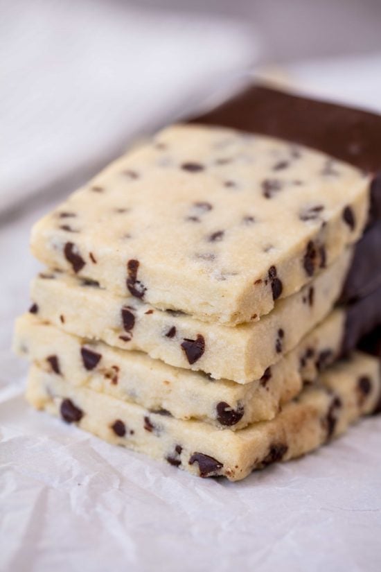 A stack of Chocolate Chip Shortbread Cookies with mini chocolate chips and dipped in melted chocolate.