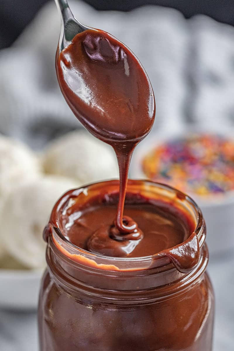 Spoon drizzling in Hot Fudge sauce into a mason jar full of hot fudge.