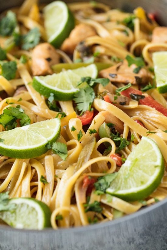 Closeup of stainless steel pan with tequila lime chicken pasta with lime slices in it