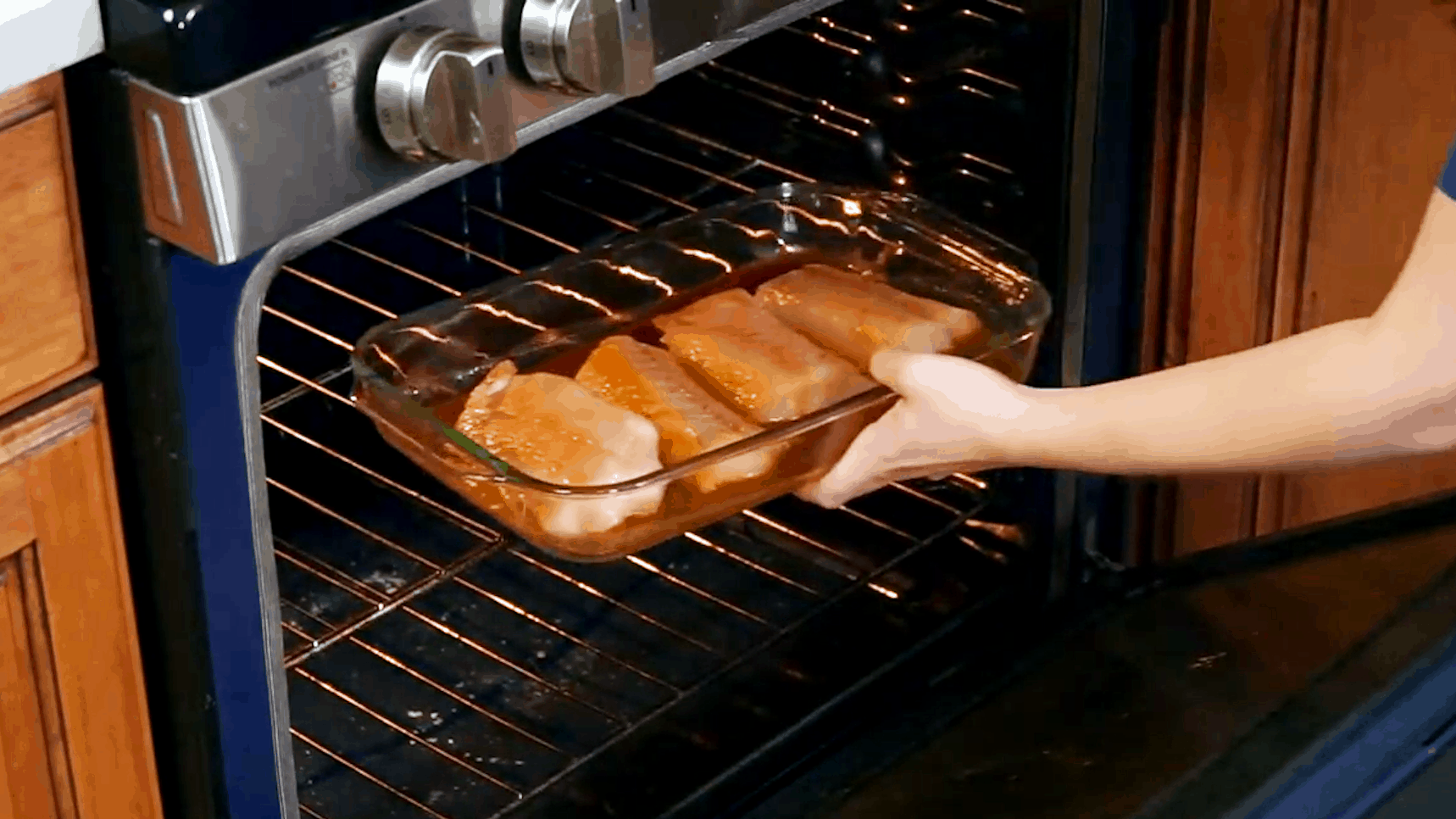 Glass 9x13 pan with 4 mahi mahi filets being placed in the oven
