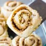 A freshly baked Baklava Cinnamon Roll is lifted from the pan