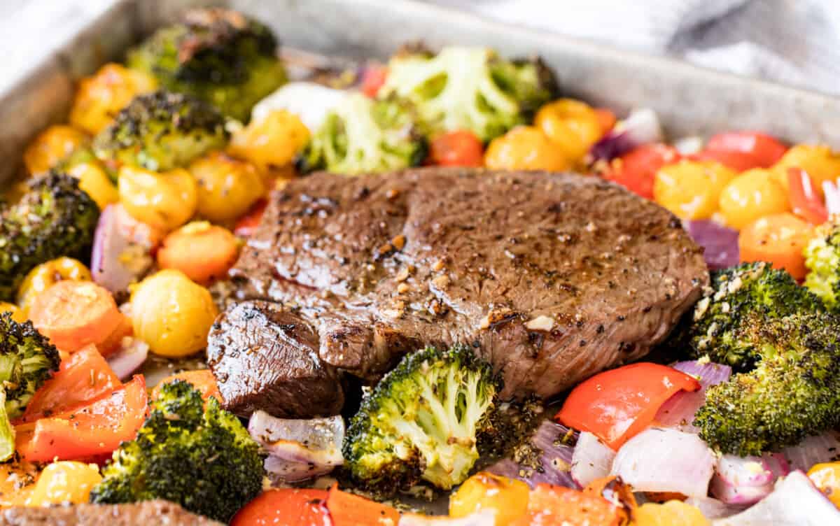 Close up of the steak on a sheet pan full of veggies and the steak..