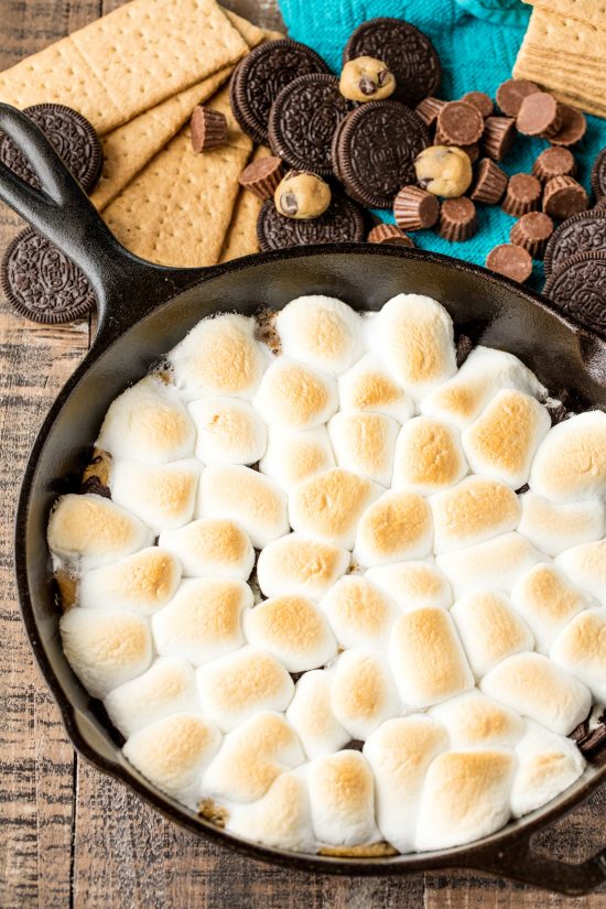 Cast iron skillet full of million dollar skilllet smore's made from marshmallow, cookie dough, oreo, and other melty goodness