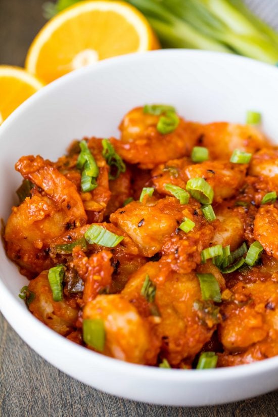 Orange Peel Shrimp in a white serving bowl tossed with fresh chopped green onion