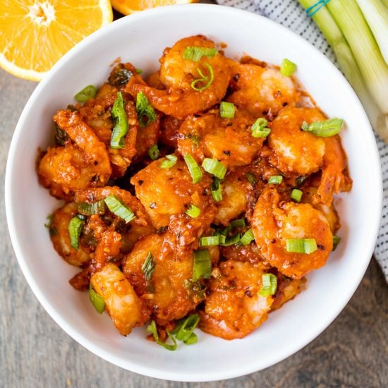 Orange Peel Shrimp in a white serving bowl tossed with fresh chopped green onion