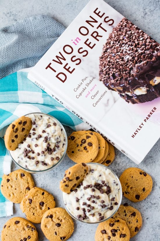 Two cups of chocolate chip cookie dough pudding next to the cookbook "Two in One Desserts" by Hayley Parker