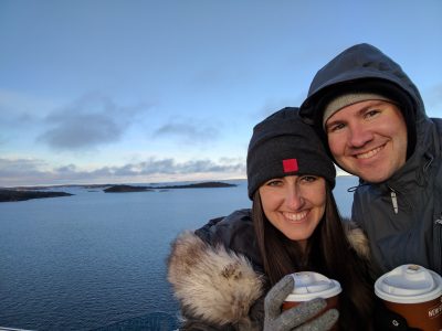 My husband and I with hot chocolate in hand with the ocean and a glimpse of Nynashamn, Sweden in the background