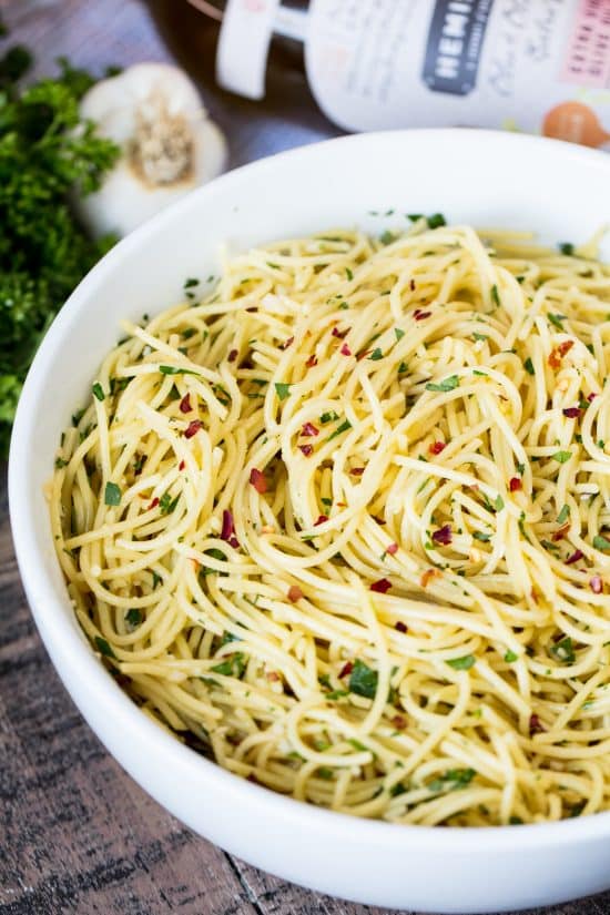 A bowl of Super Easy Olive Oil Pasta, seasoned with red pepper flakes and chopped fresh parsley