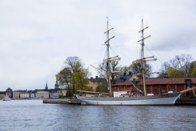 A sailboat docked in a bay, the city of Stockholm, Sweden in the background