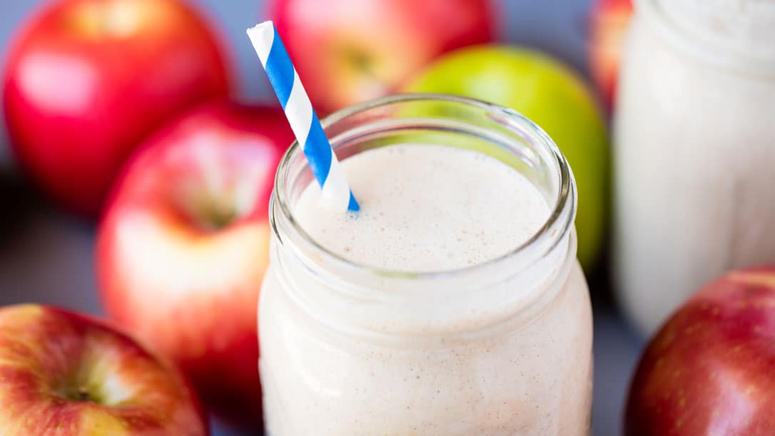 Make-ahead apple pie oatmeal smoothie in a mason jar with a blue and white straw