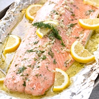 Baked Salmon that has lemon slices, dill, garlic, and butter on it