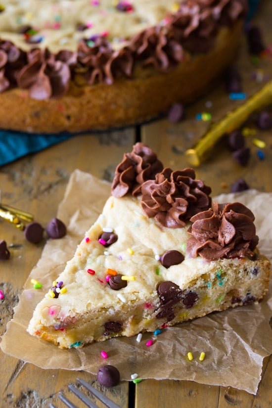 Slice of chocolate chip cookie cake sitting on some wax paper. 