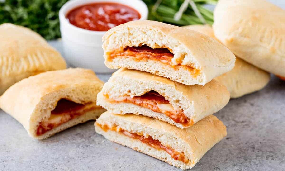 A stack of Homemade Hot Pockets filled with pepperoni, mozzarella and marinara sauce, set on a concrete countertop.