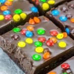 Close up of M&M Fudge Brownies cut into squares on wax paper.