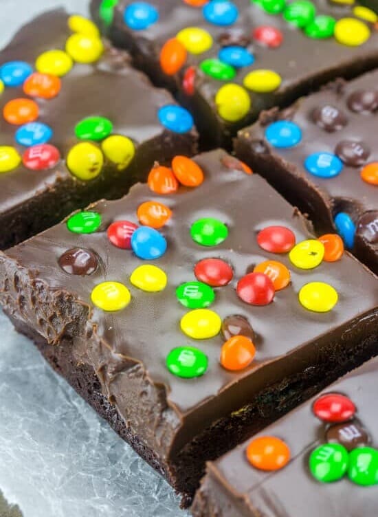 Close up of M&M Fudge Brownies cut into squares on wax paper.