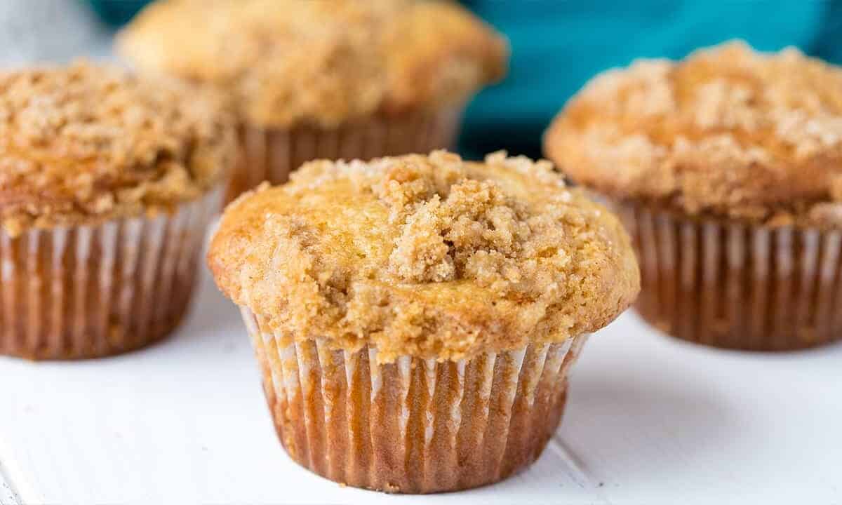 Close-up view of Sour Cream Coffee Cake Muffins on white painted wood table top.